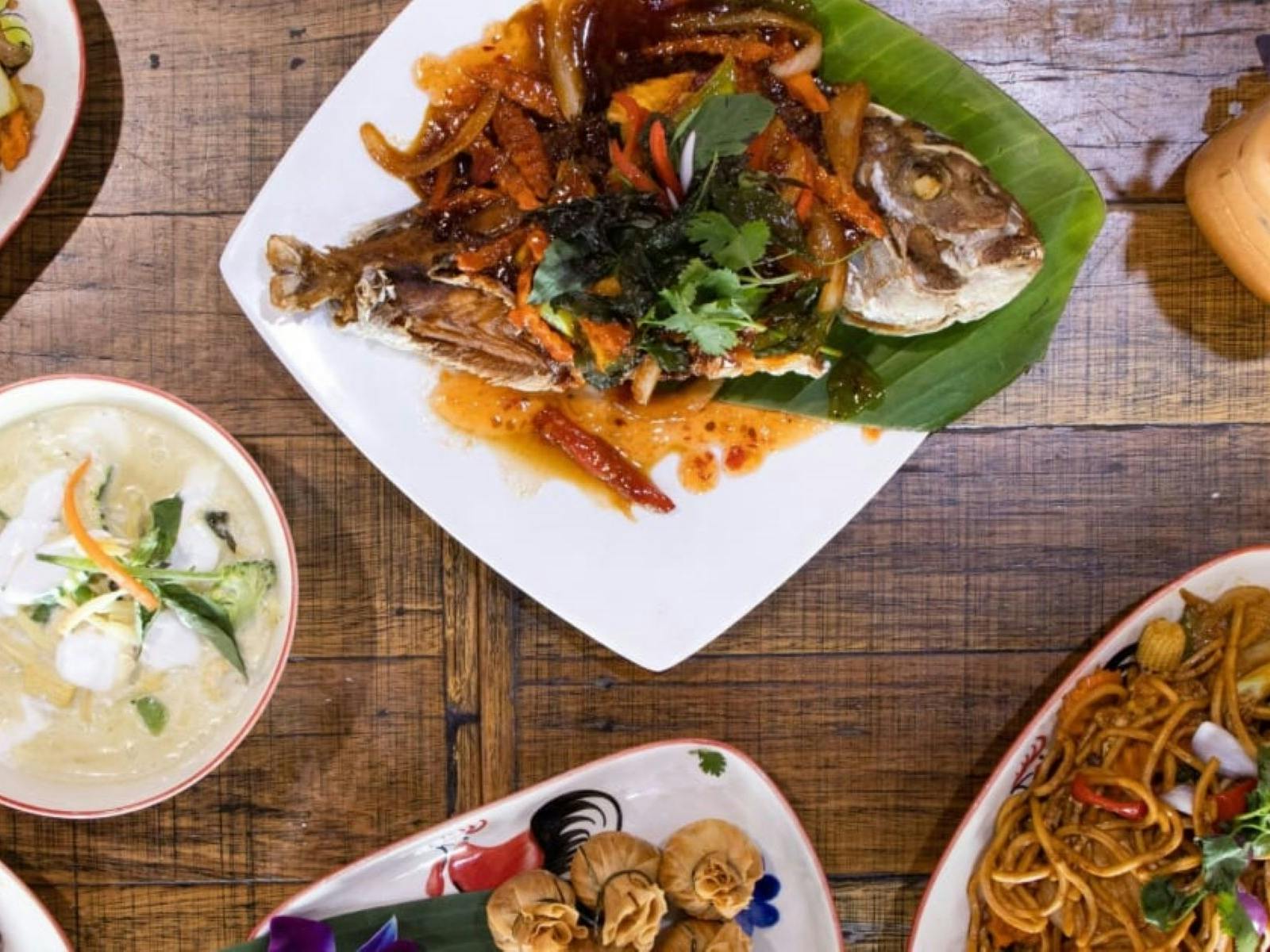 A table with a drink and 4 different Thai meals and a soup.