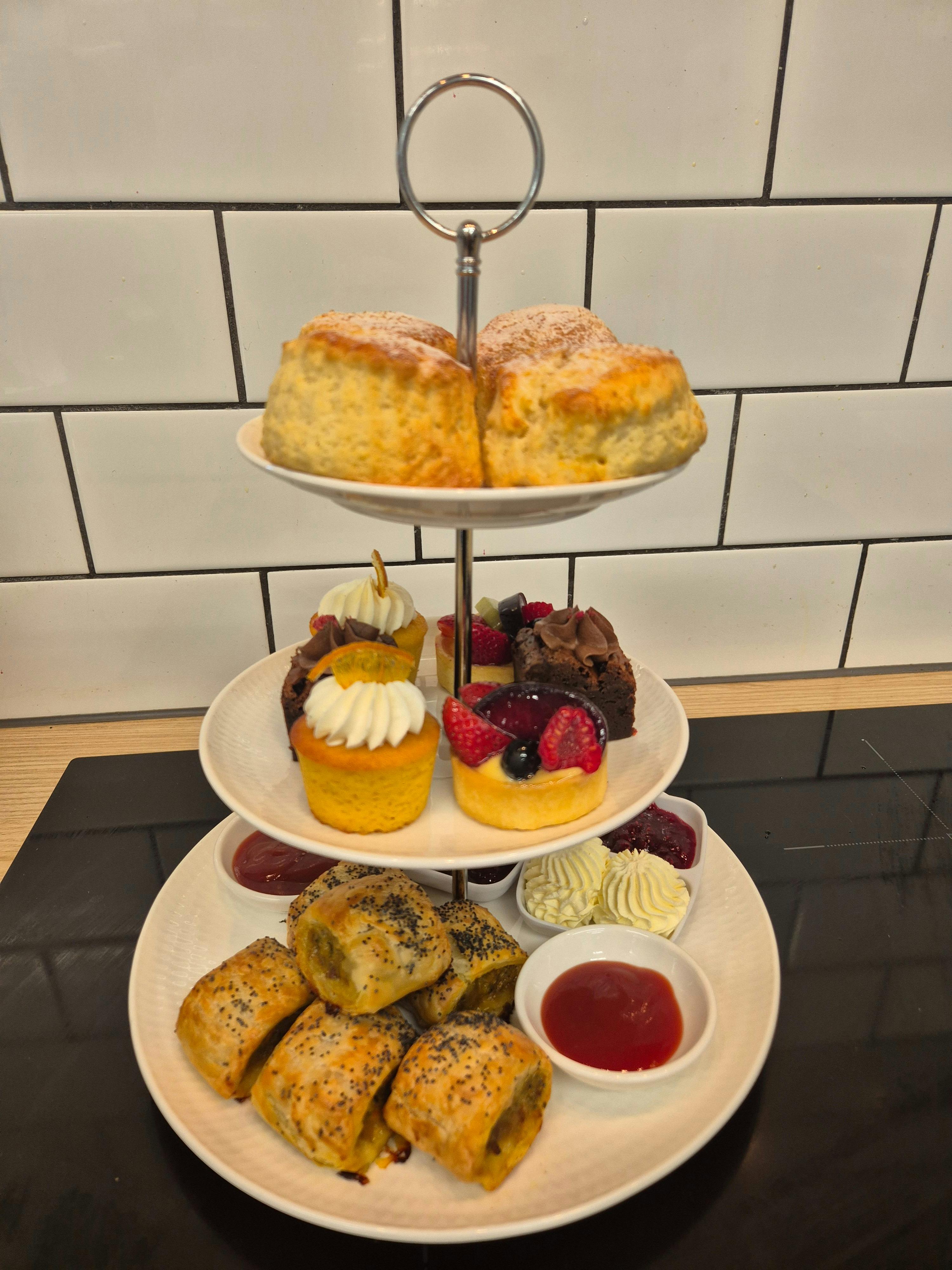scones, tarts and sausage rolls with sauce on a tiered stand