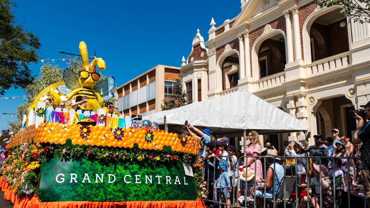 The grand central floral parade float with flowers and bee all decorated on it. People cheering