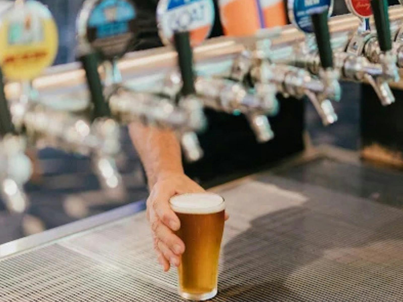 bar taps with someone holding a beer that has just been poured