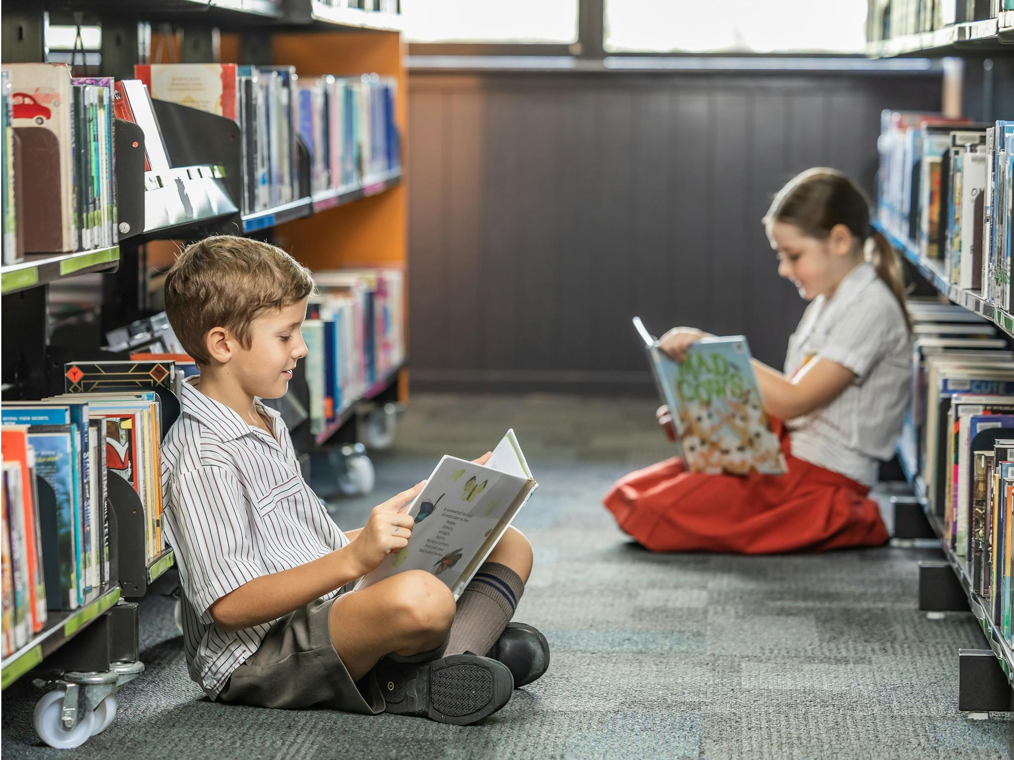 Two children in library reading books Two children in library reading books