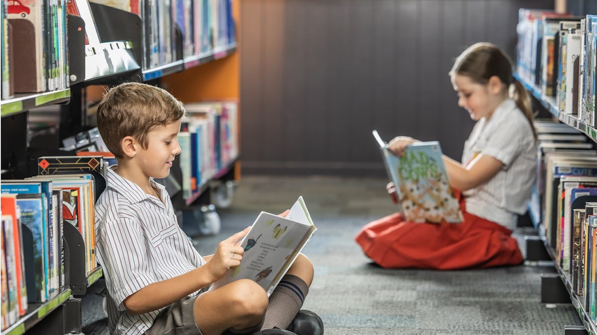 Two children in library reading books