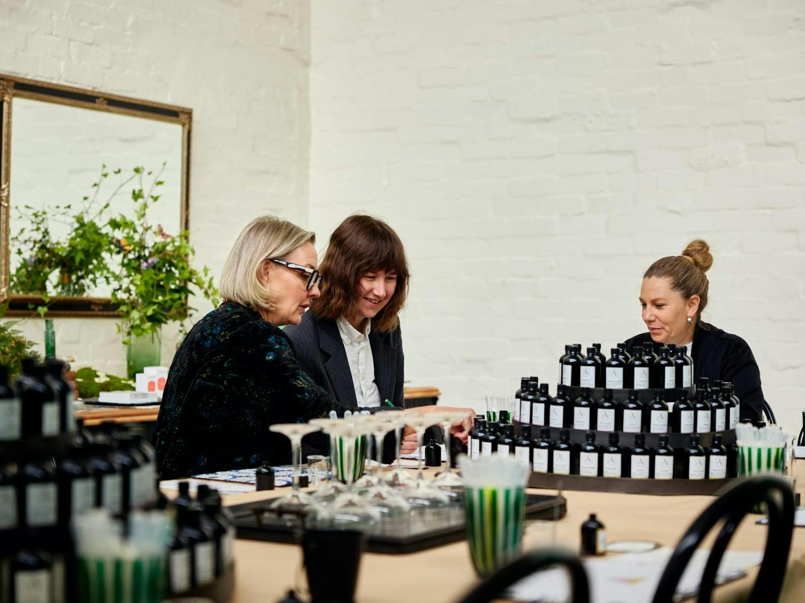 three women looking at stacks of fragrance bottles