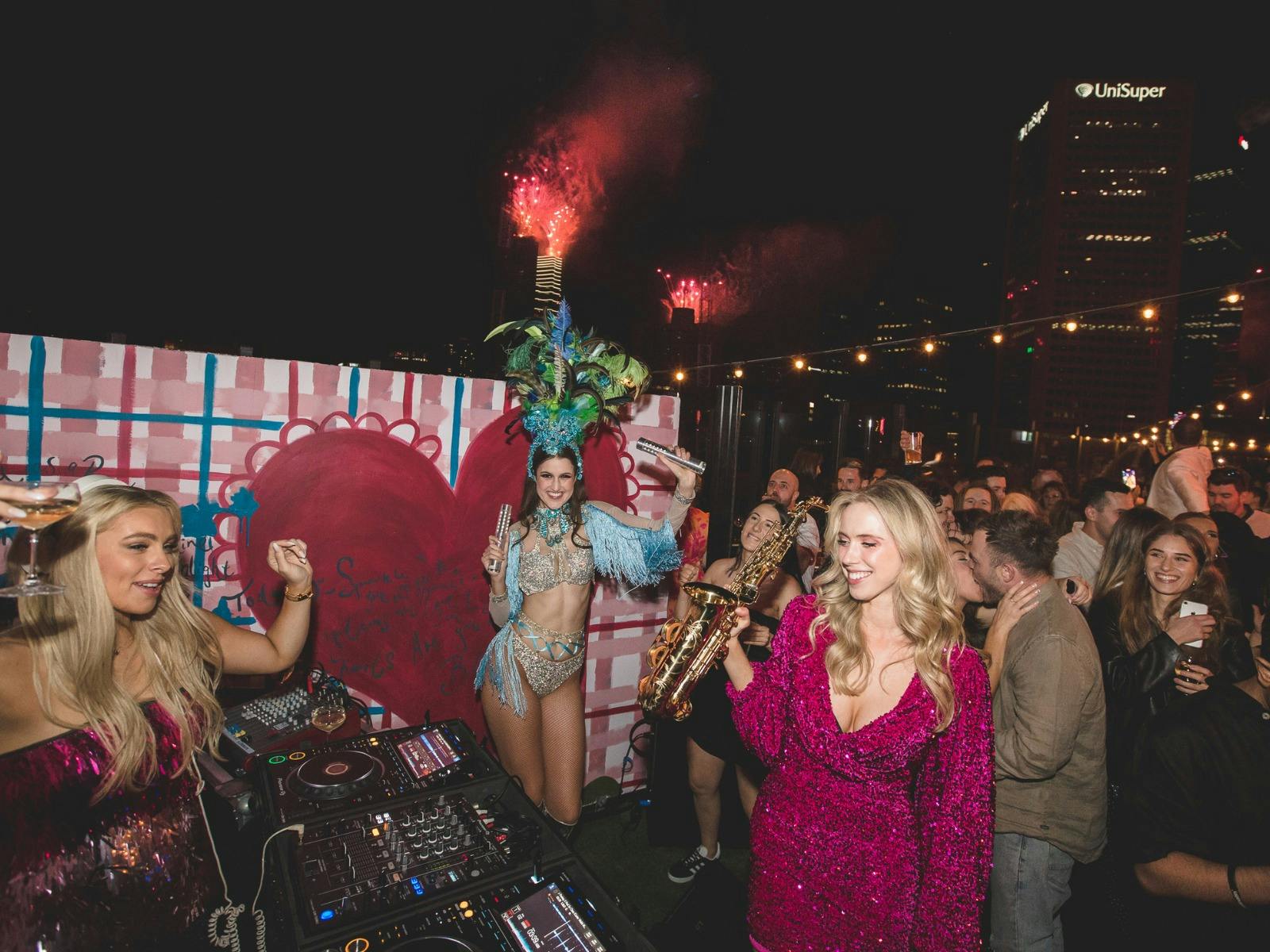 fireworks and people celebrating at a rooftop bar