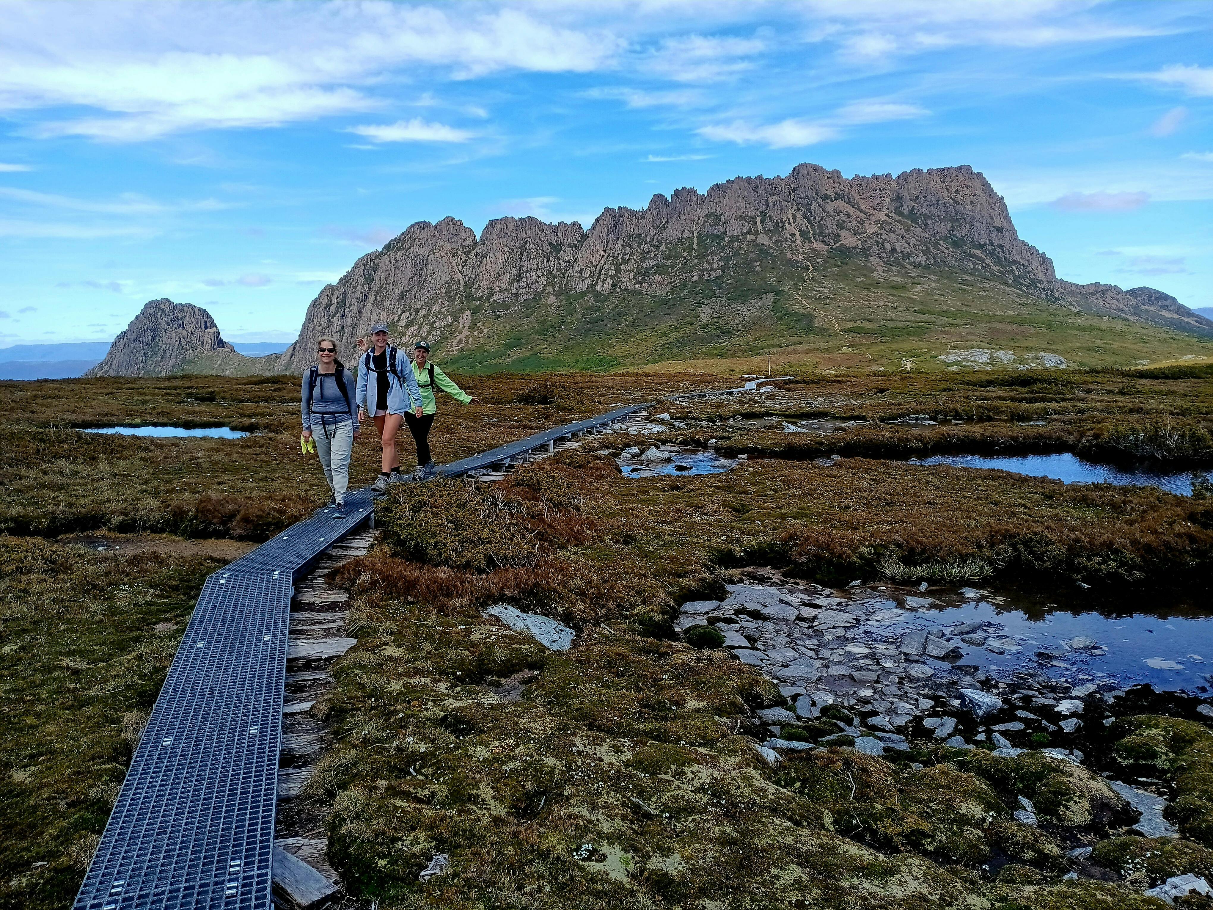 Walkers on boardwalk with Cradle Mountain in the background Tasmania alpine walking track.