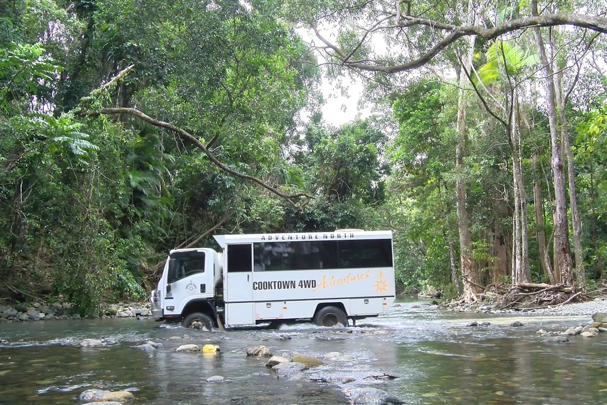 Custom built Cooktown 4WD coach driving across creek crossing.