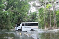 Custom built Cooktown 4WD coach driving across creek crossing.