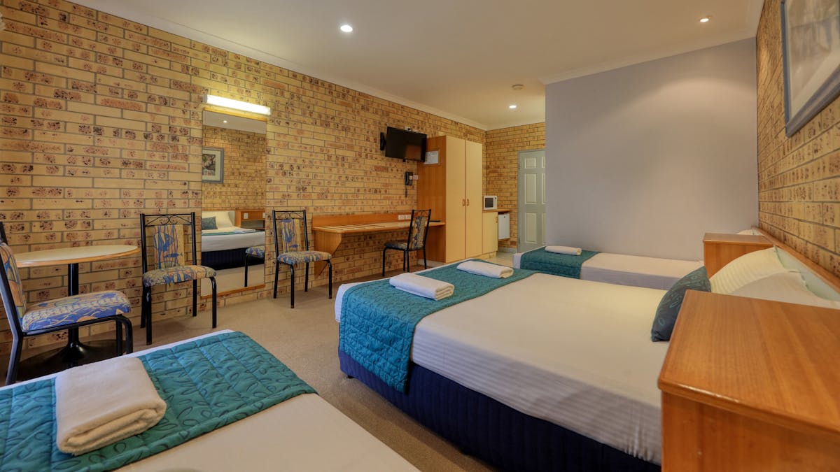 Room photo showing 1 queen and 2 single beds, bench, chairs and cupboard