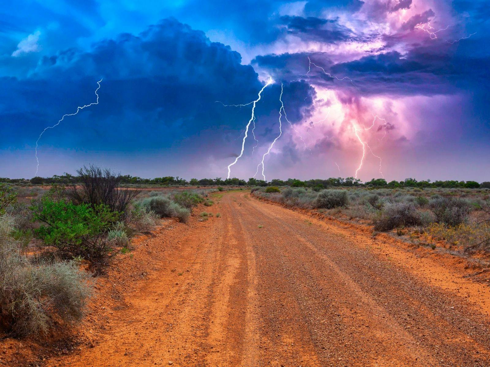 lightning striking in the distance while on a country dirt road