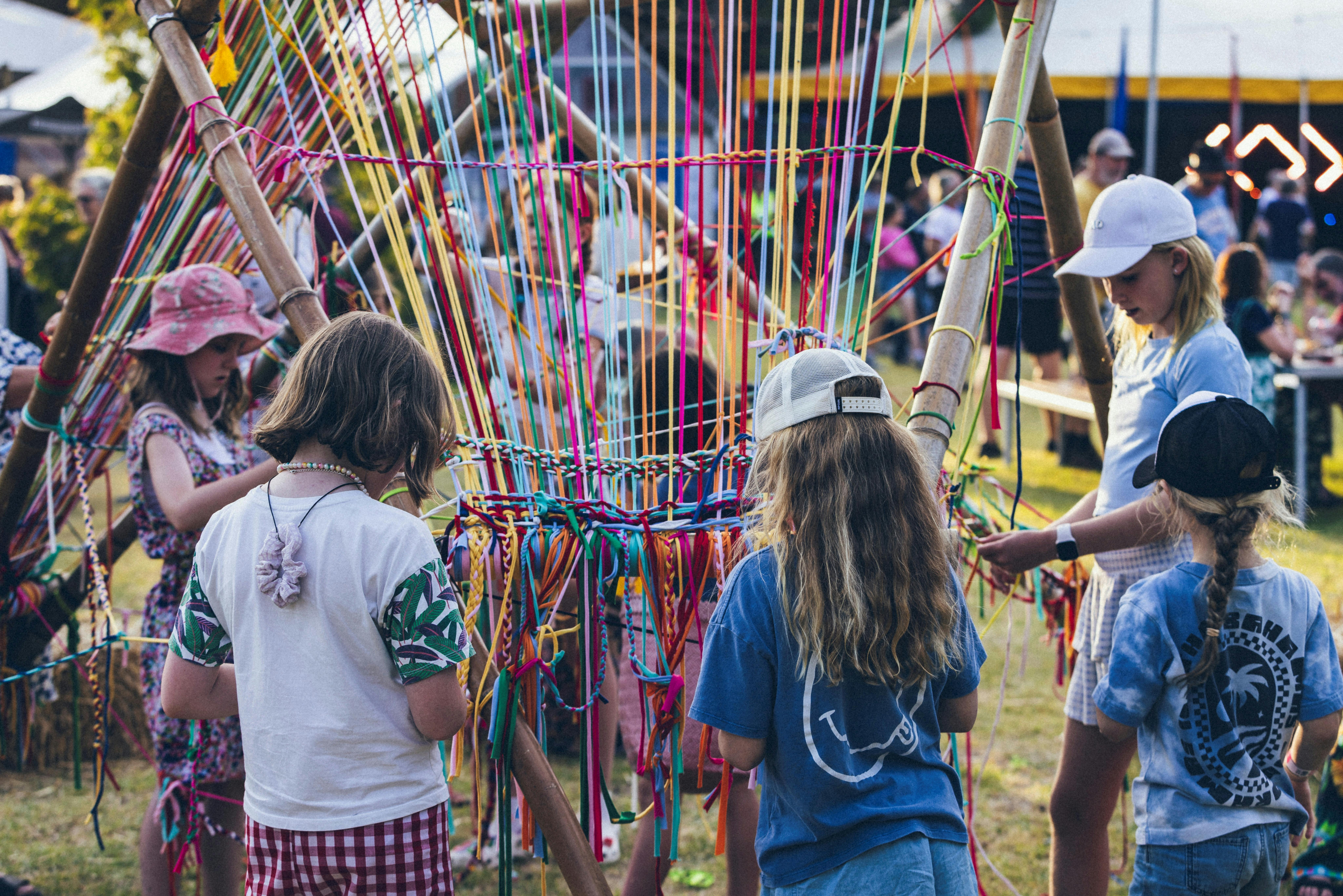 Children weaving at an art installation