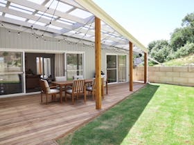 Timber deck with dining table and chairs under string lights