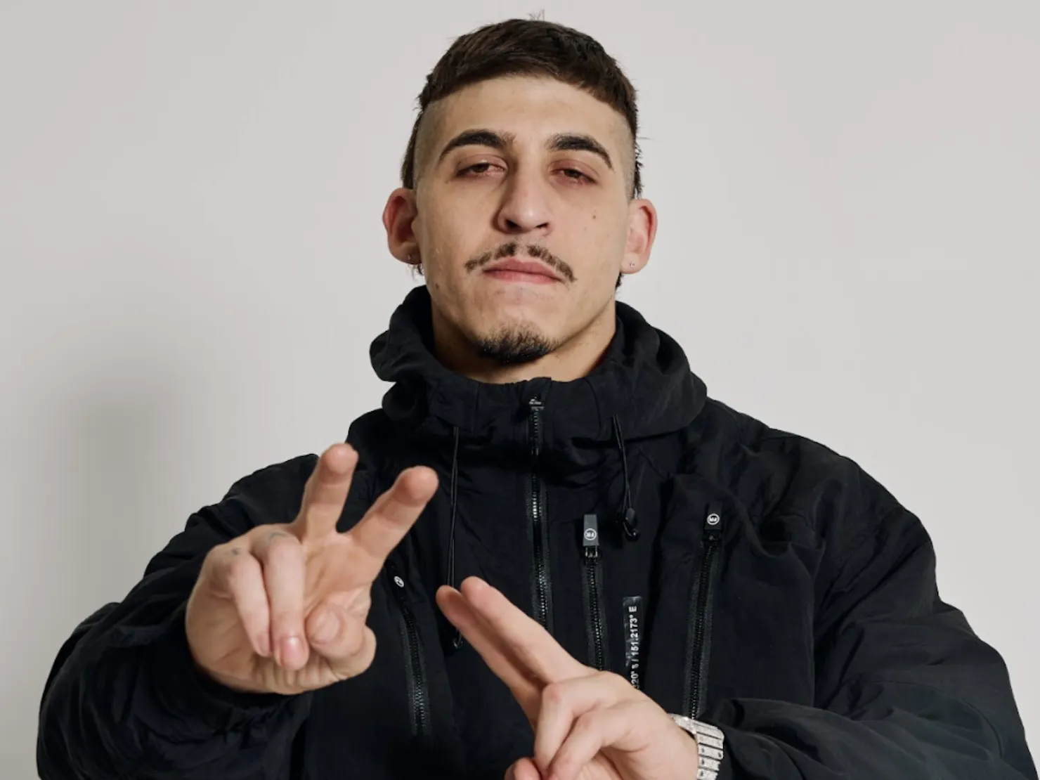 Artist posing for photo with two hands up in a black outfit