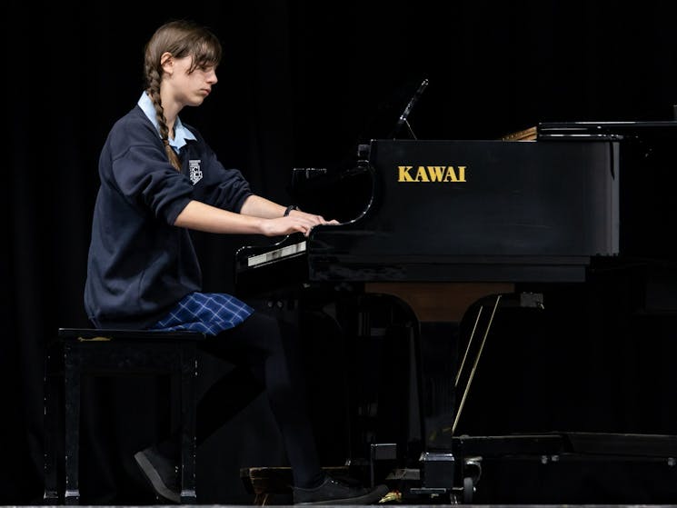 Young woman playing a grand piano during a competition