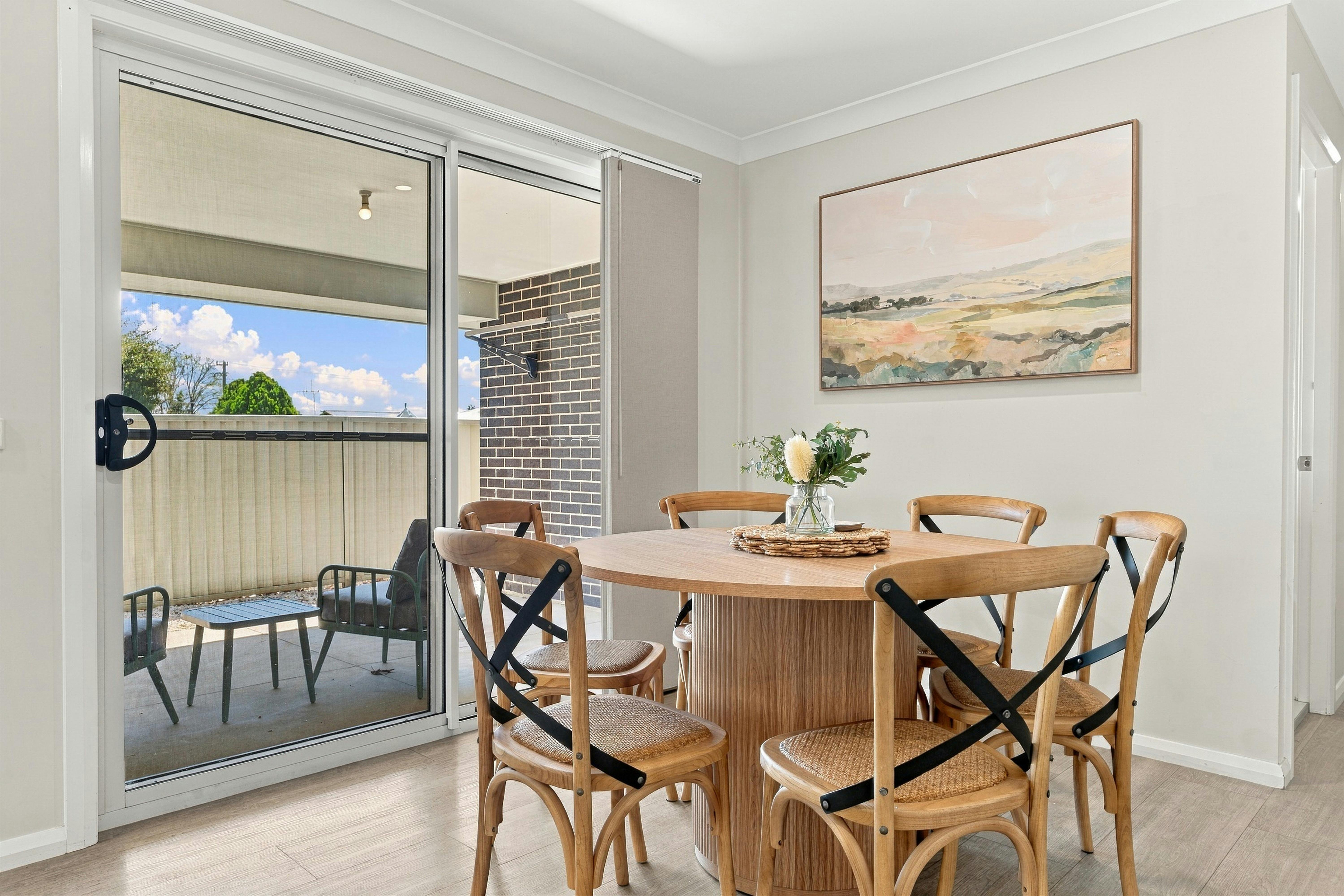 Dining table with 6 chairs, artwork and sliding door to outside