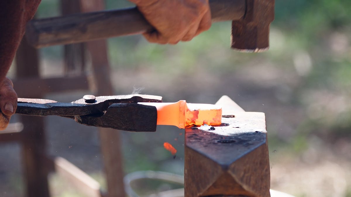 blacksmith hammers red-hot steel on an anvil