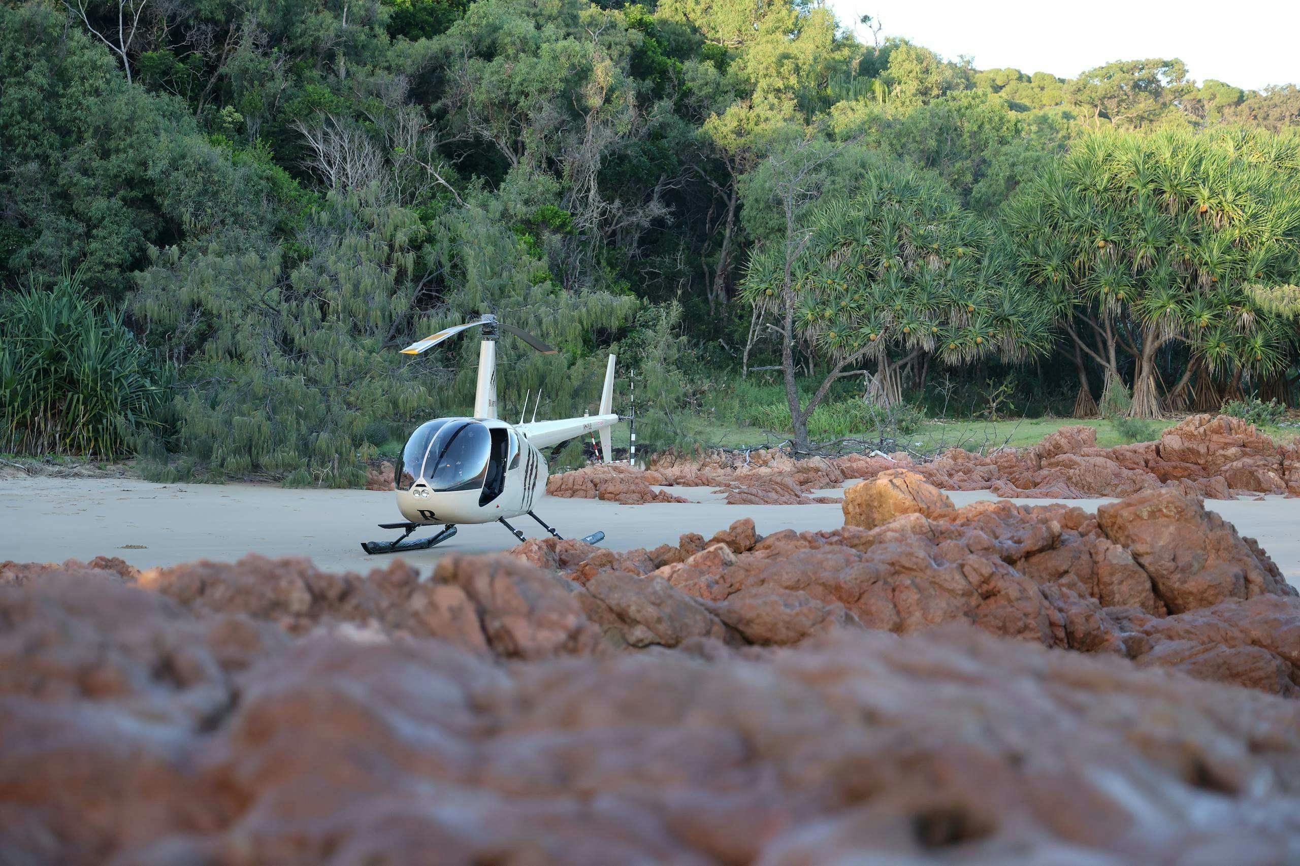 Helicopter sitting on the sand between rocks