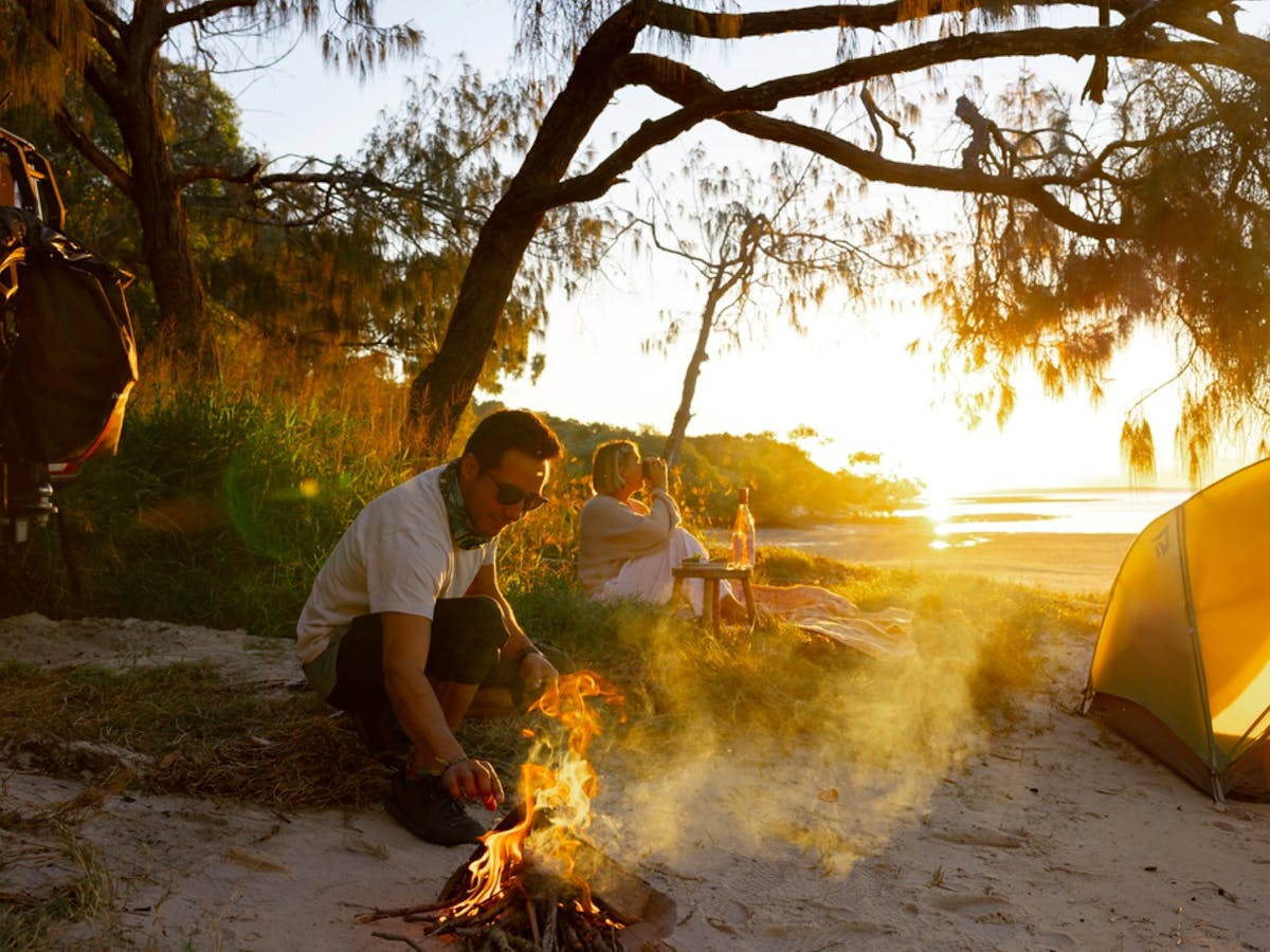 A couple having a fire while the sunsets