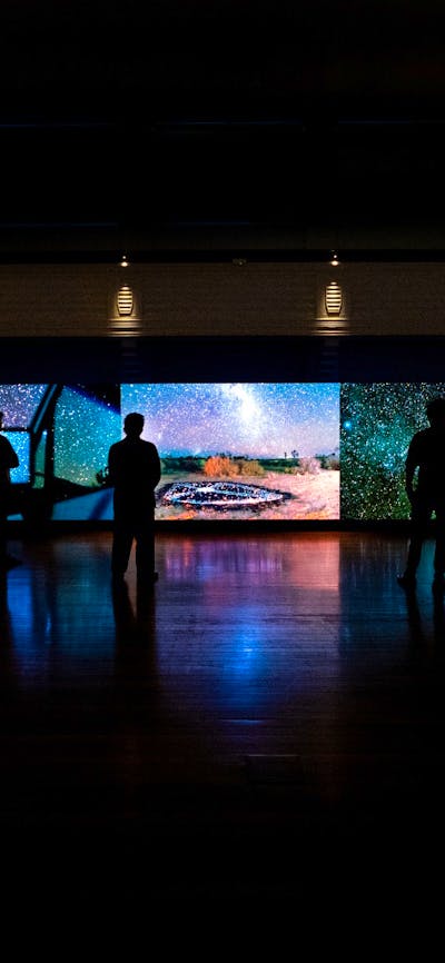 Dark gallery space with shadows and outlines of people in the space
