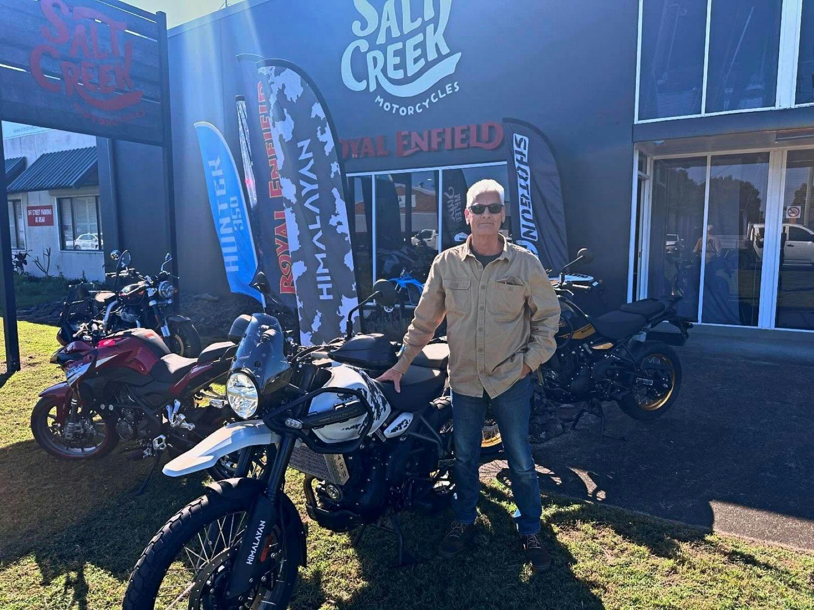 Man at front of shop with motorcycles