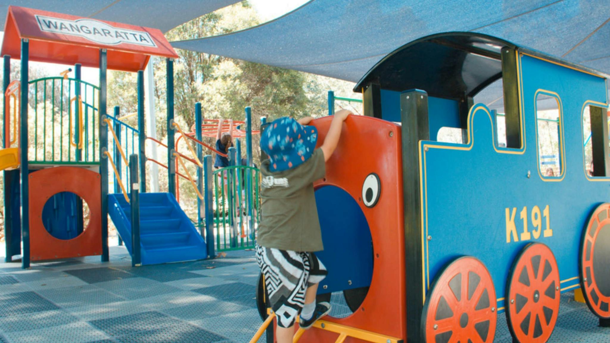 Children's playground, replica train with child climbing, in back ground climbing frame, child, tree