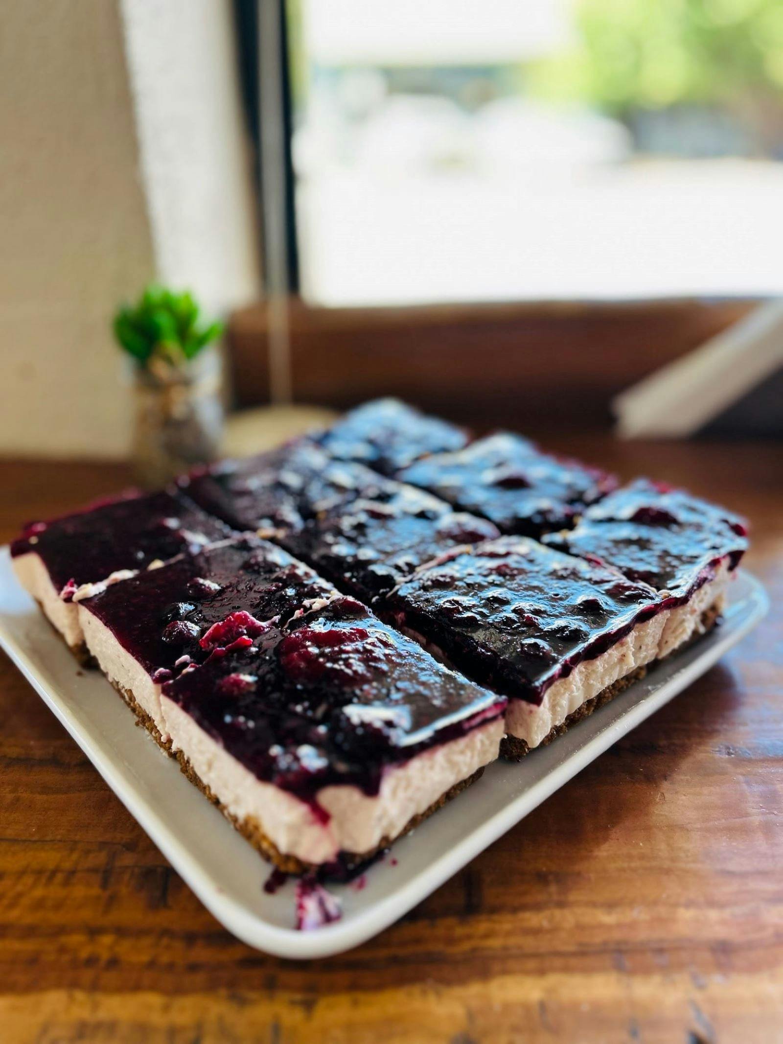 Close up of homemade berry cheesecake, cut into squares.