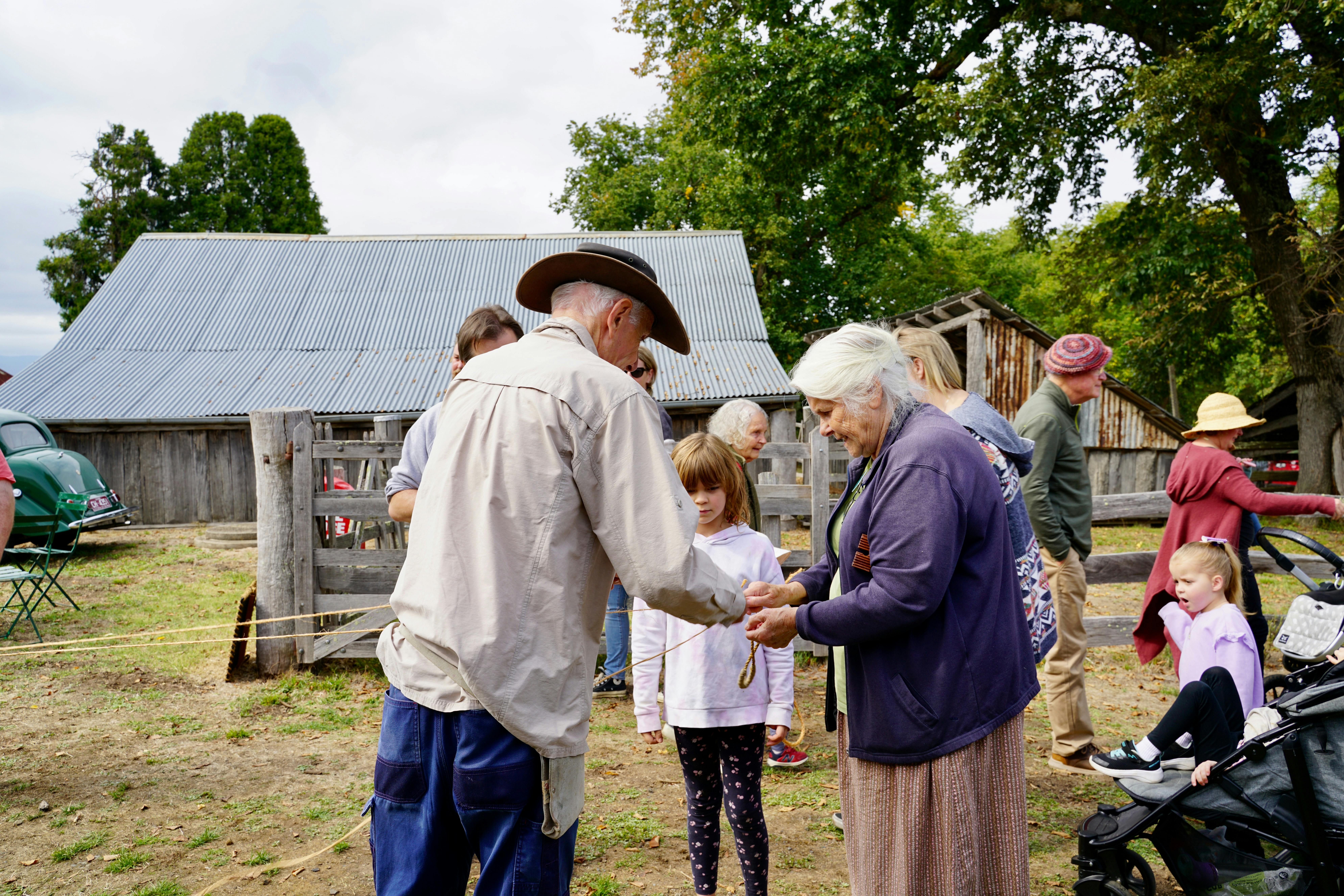 Two Gulf Station volunters rope making with a young girl looking onn