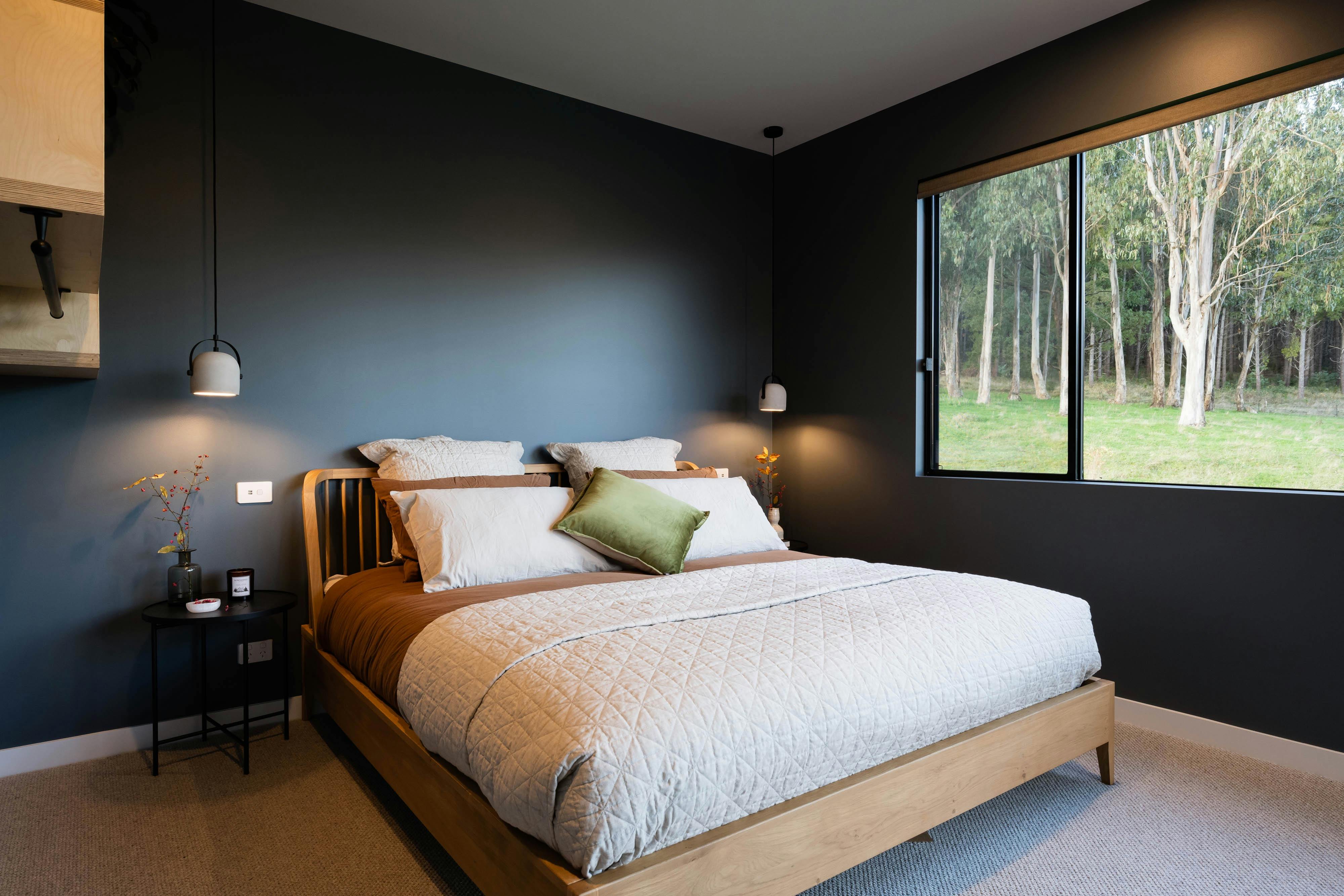 Moody master bedroom with large windows and views to gumtrees and mountains