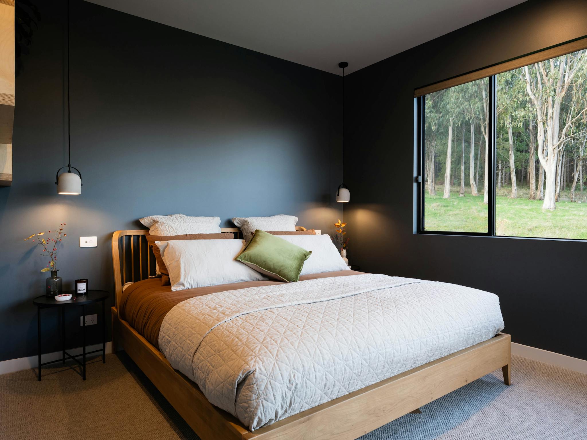 Moody master bedroom with large windows and views to gumtrees and mountains