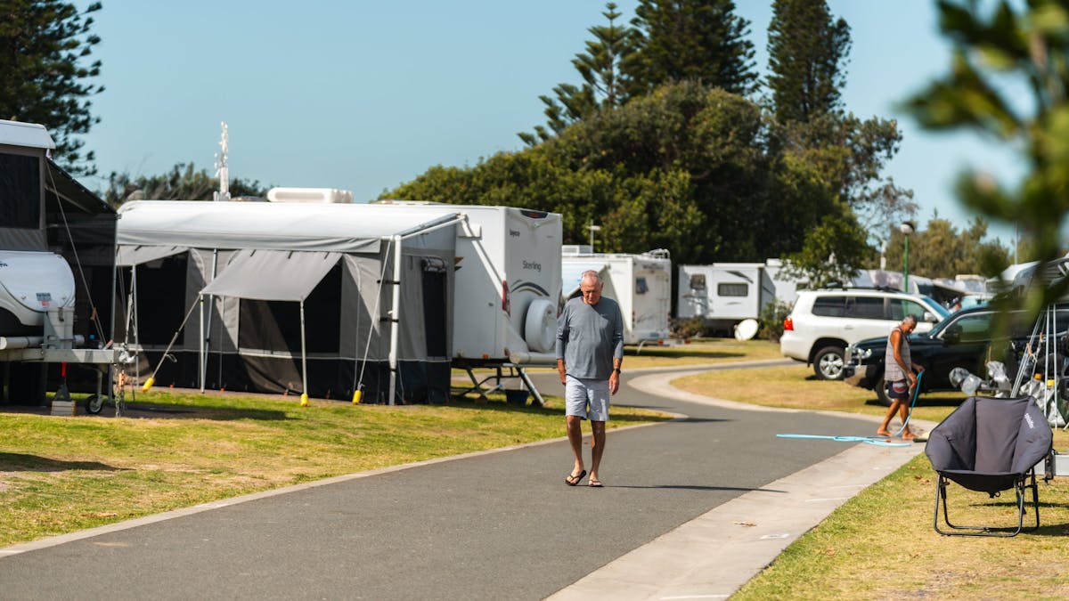 Image of a man walking through the caravan park. Image is zoomed out to see multiple caravans