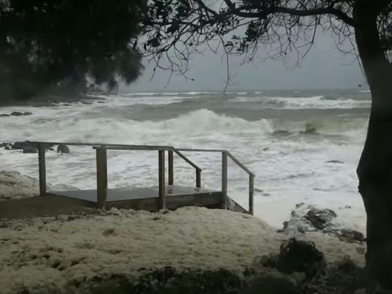 Stormy seas at high tide crashing over the steps to the beach.