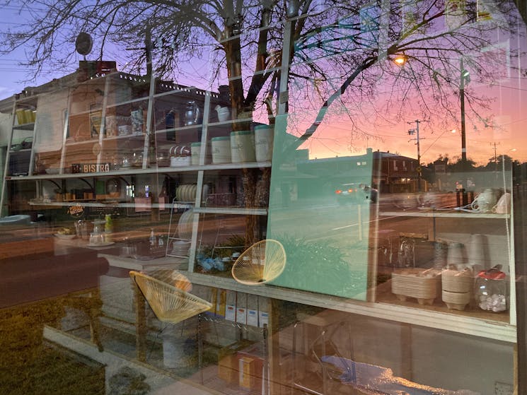 Colourful sunrise and reflection of shop shelving through shop window.