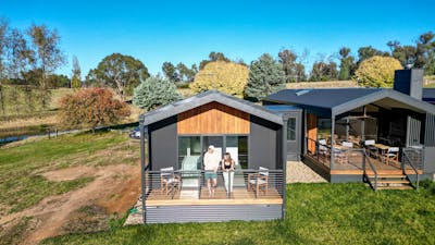 Guests standing on a private balcony of a modern cabin overlooking rural landscapes.