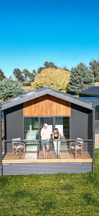 Guests standing on a private balcony of a modern cabin overlooking rural landscapes.