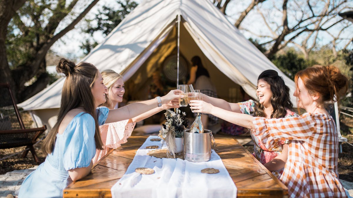 Four girlfriends enjoy gourmet picnic with bell tent