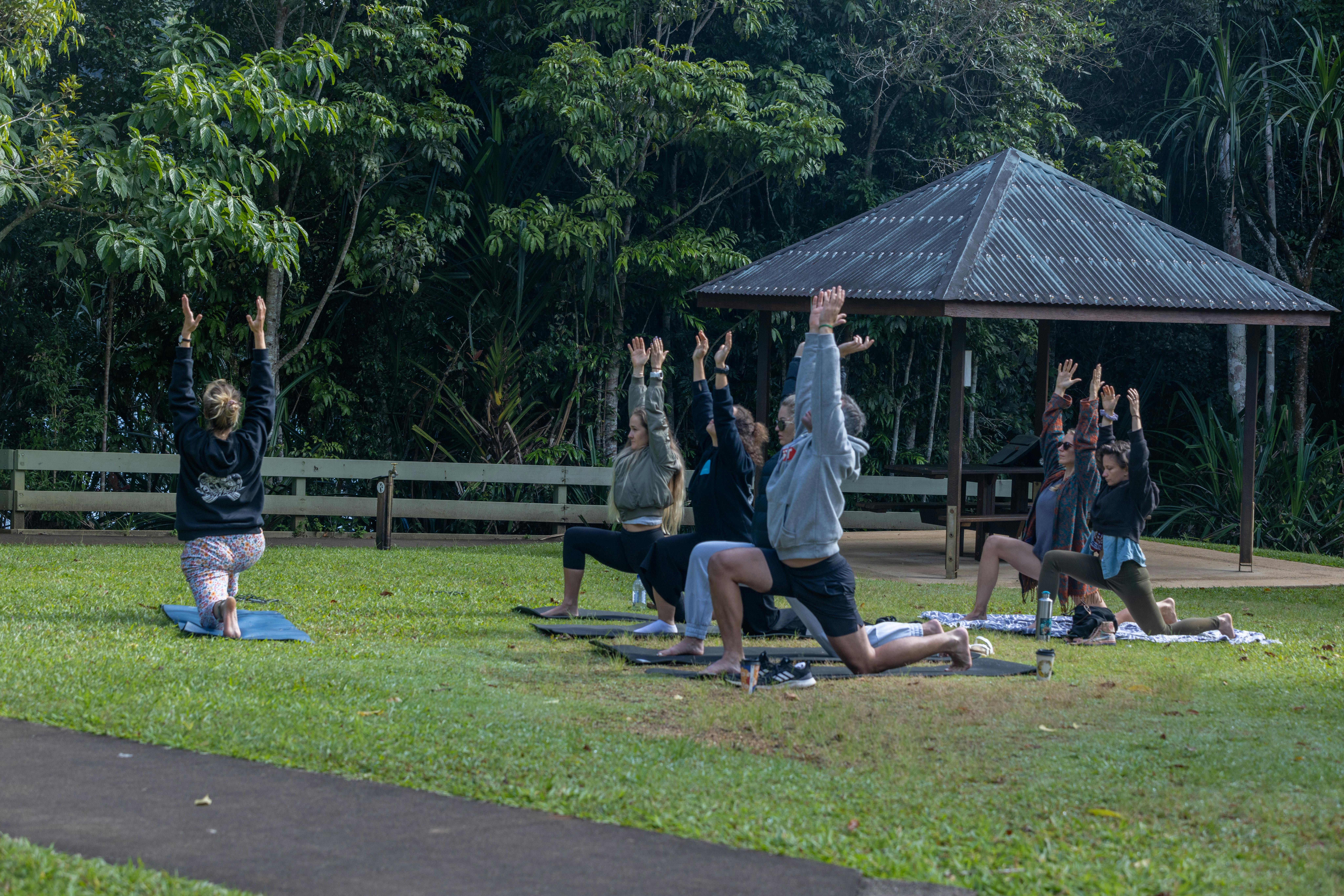 Instructor with group of 5 students doing stretching and yoga on the grass by the lake