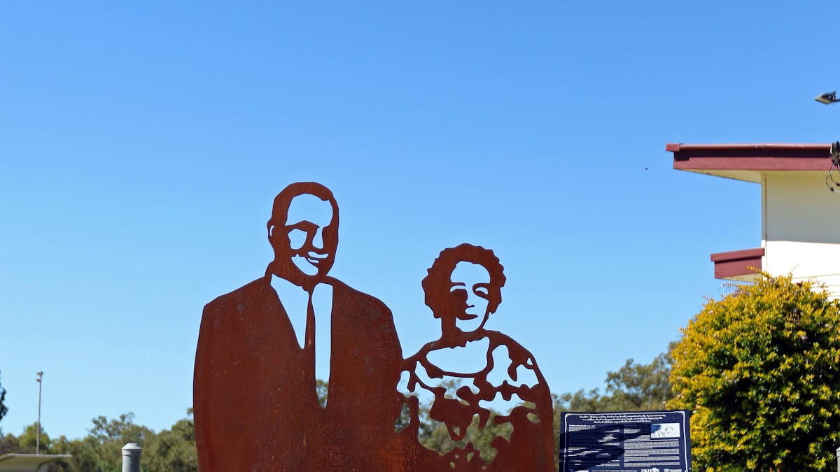 A metal lasercut sculpture of a man in a suit and a woman in a floral dress