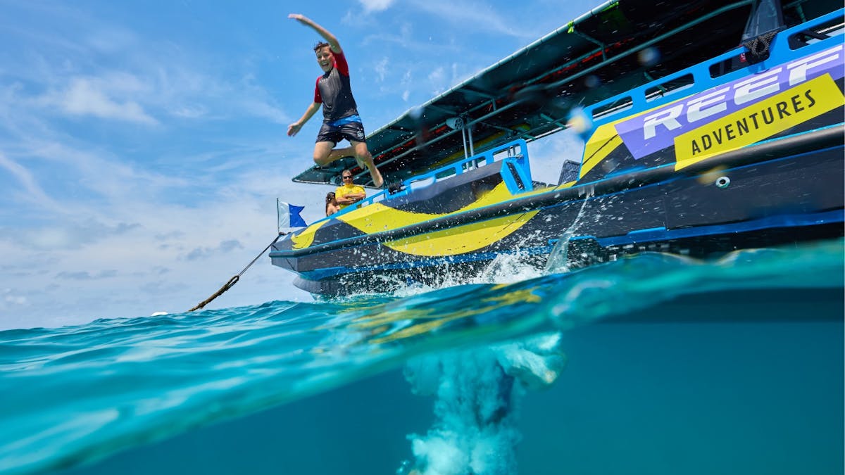 An individual jumping from the boats edge into the water.
