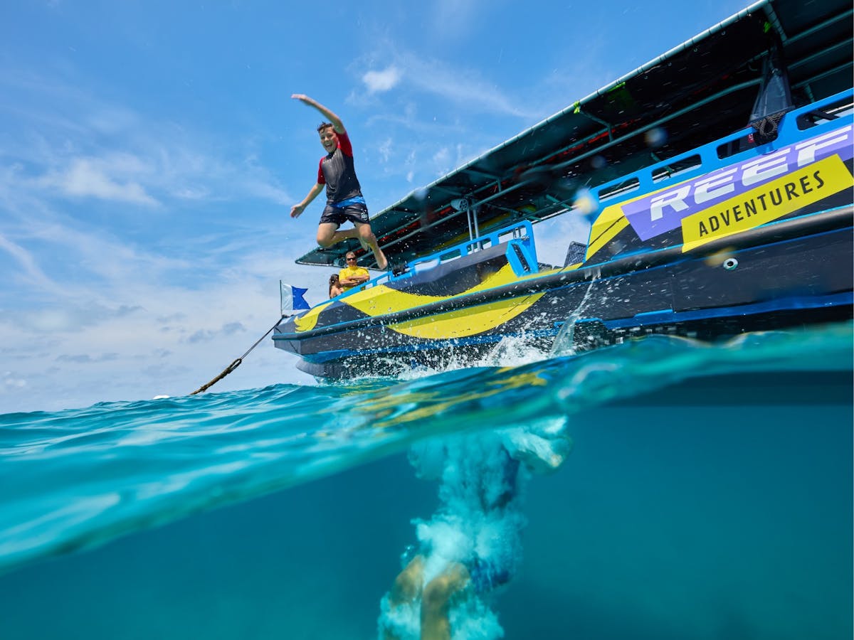 An individual jumping from the boats edge into the water.