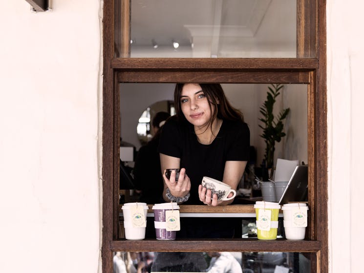 Female in window of cafe, order here sign above