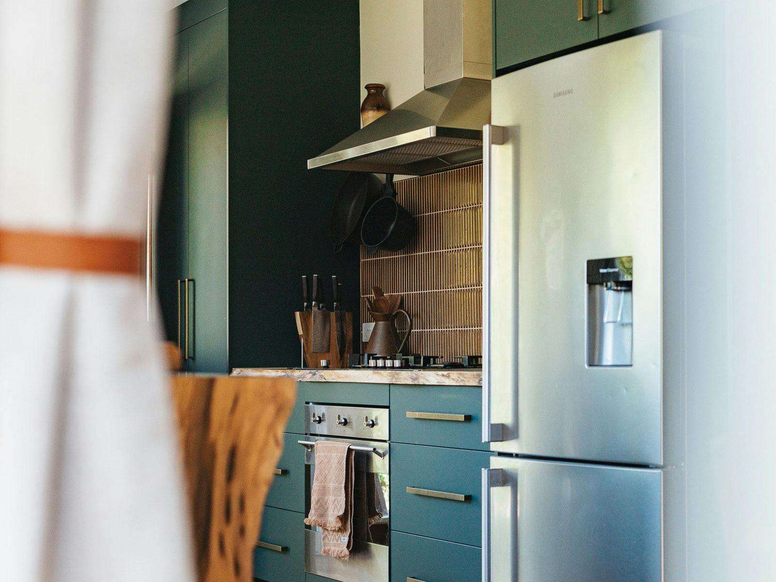 Galley kitchen with oven, stove, fridge and pantry.