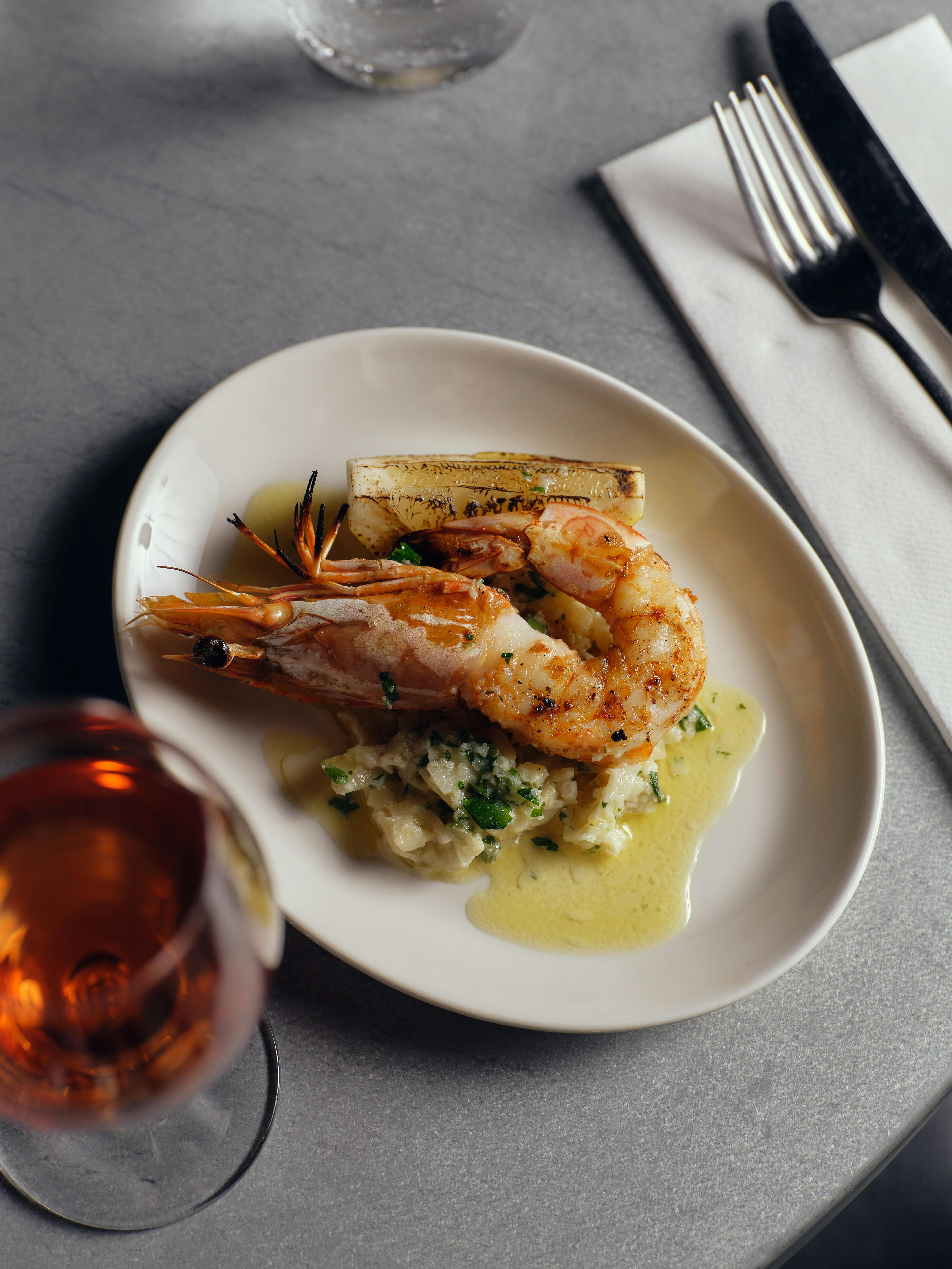 whole prawn on an oval white plate with buttery fennel