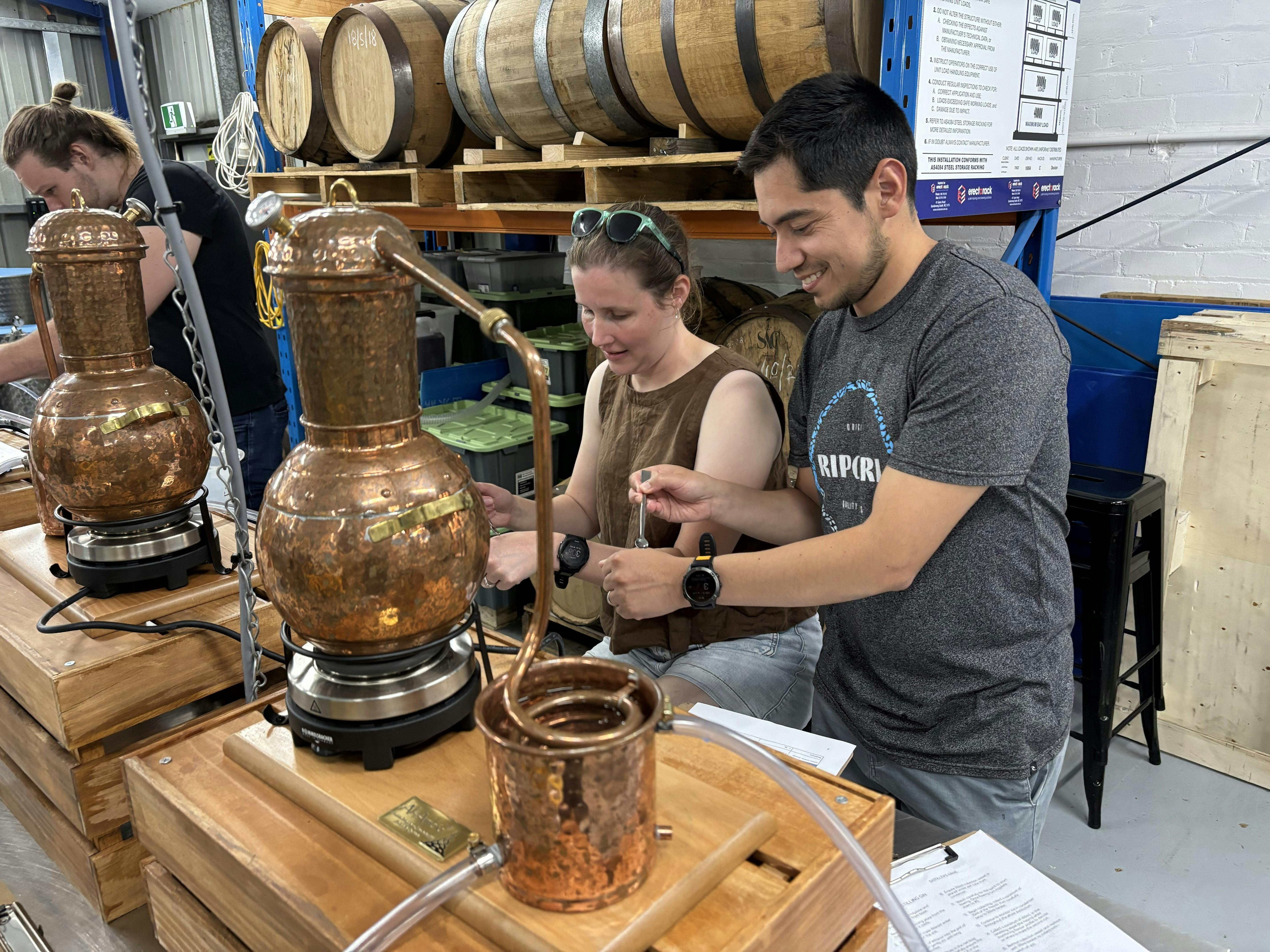 Two adults working with small still in bench