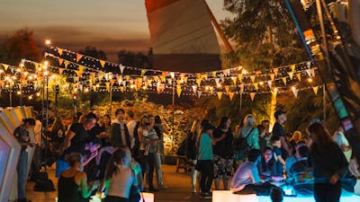 Outdoor evening festival with colourful bunting and string lights.