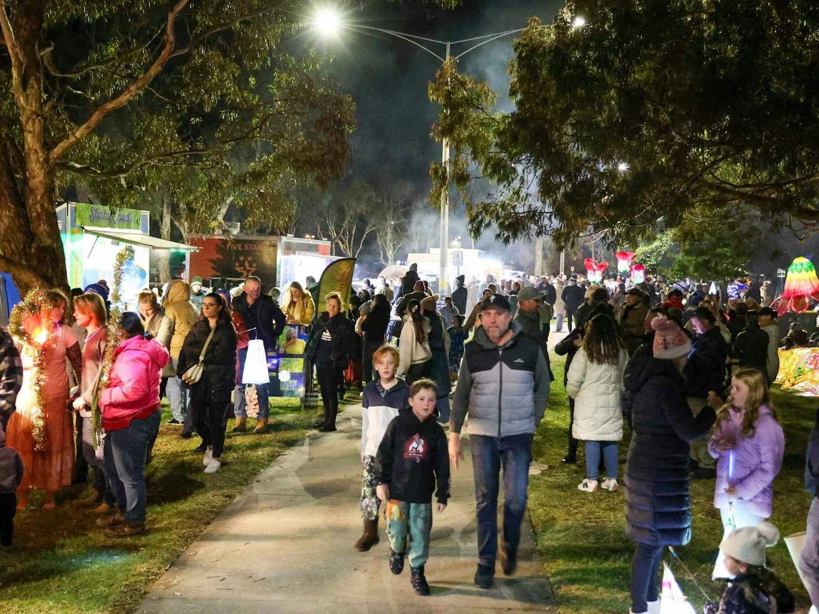 A large crowd of people gathered, with food trucks and lanterns
