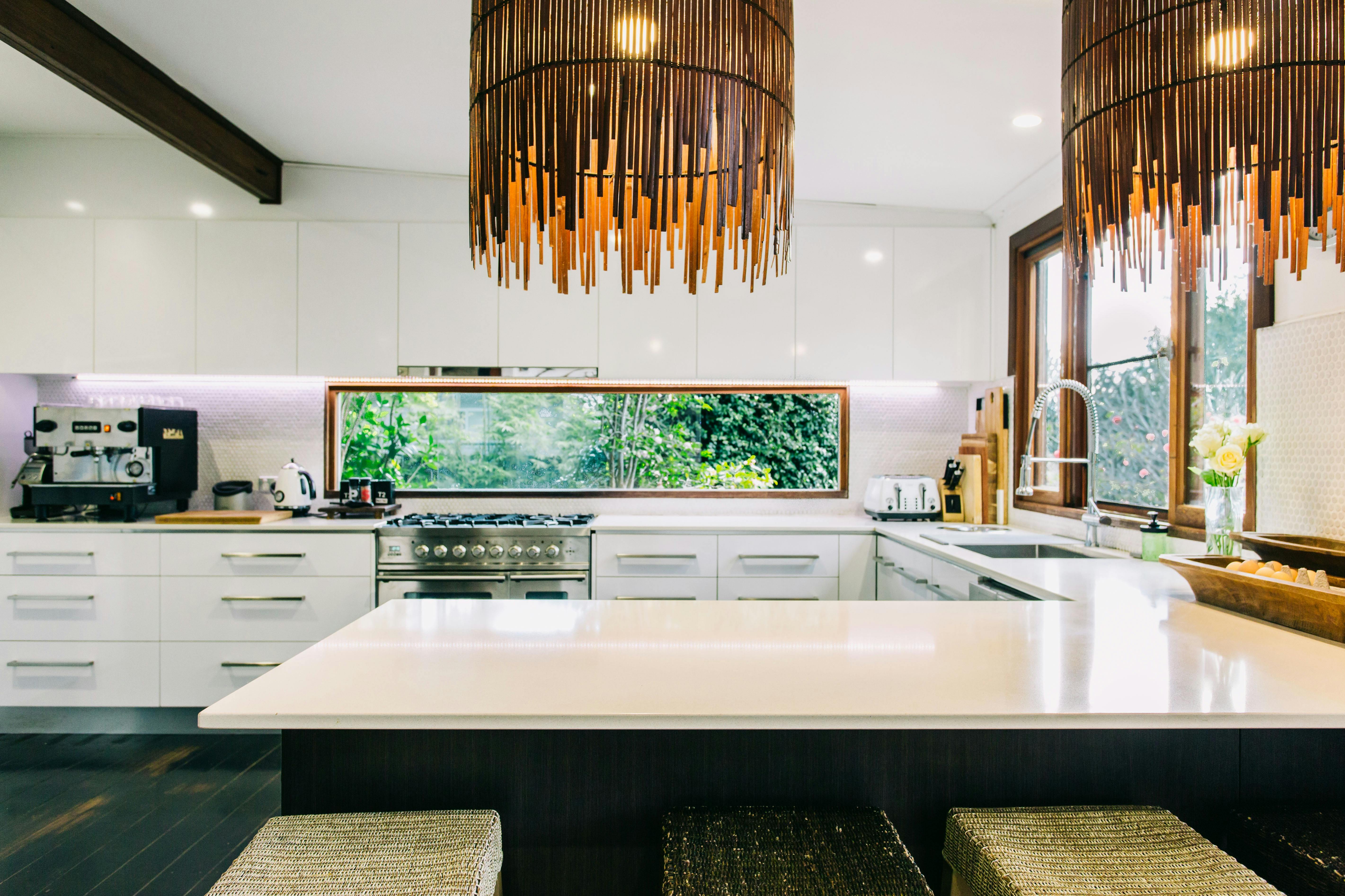 White clean kitchen with beautiful lamp shades and large benchtops to create  fabulous meals
