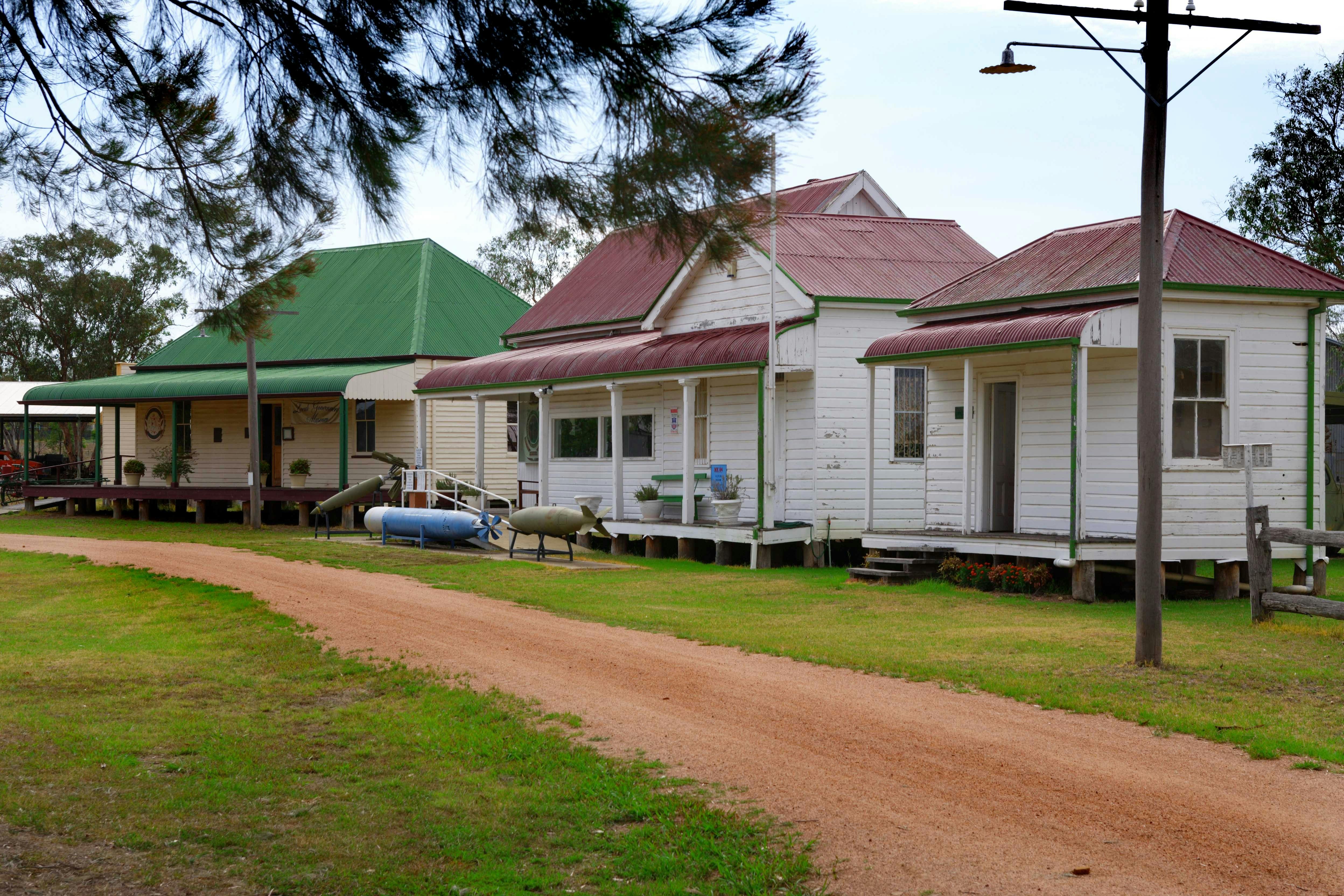 Three buildings on right with gravel pathway running in front of them