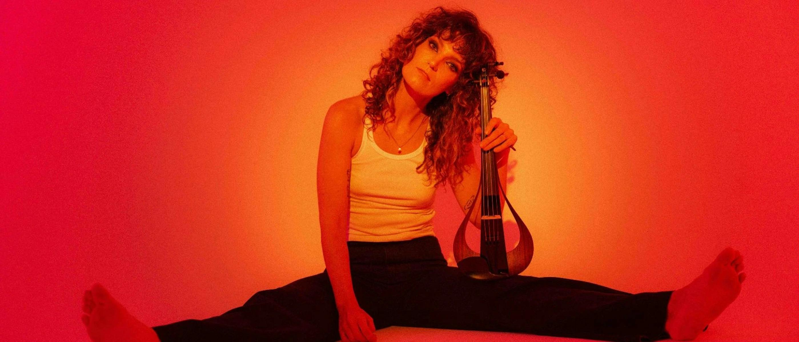 A woman sitting on the floor, holding a musical instrument, with bare feet.