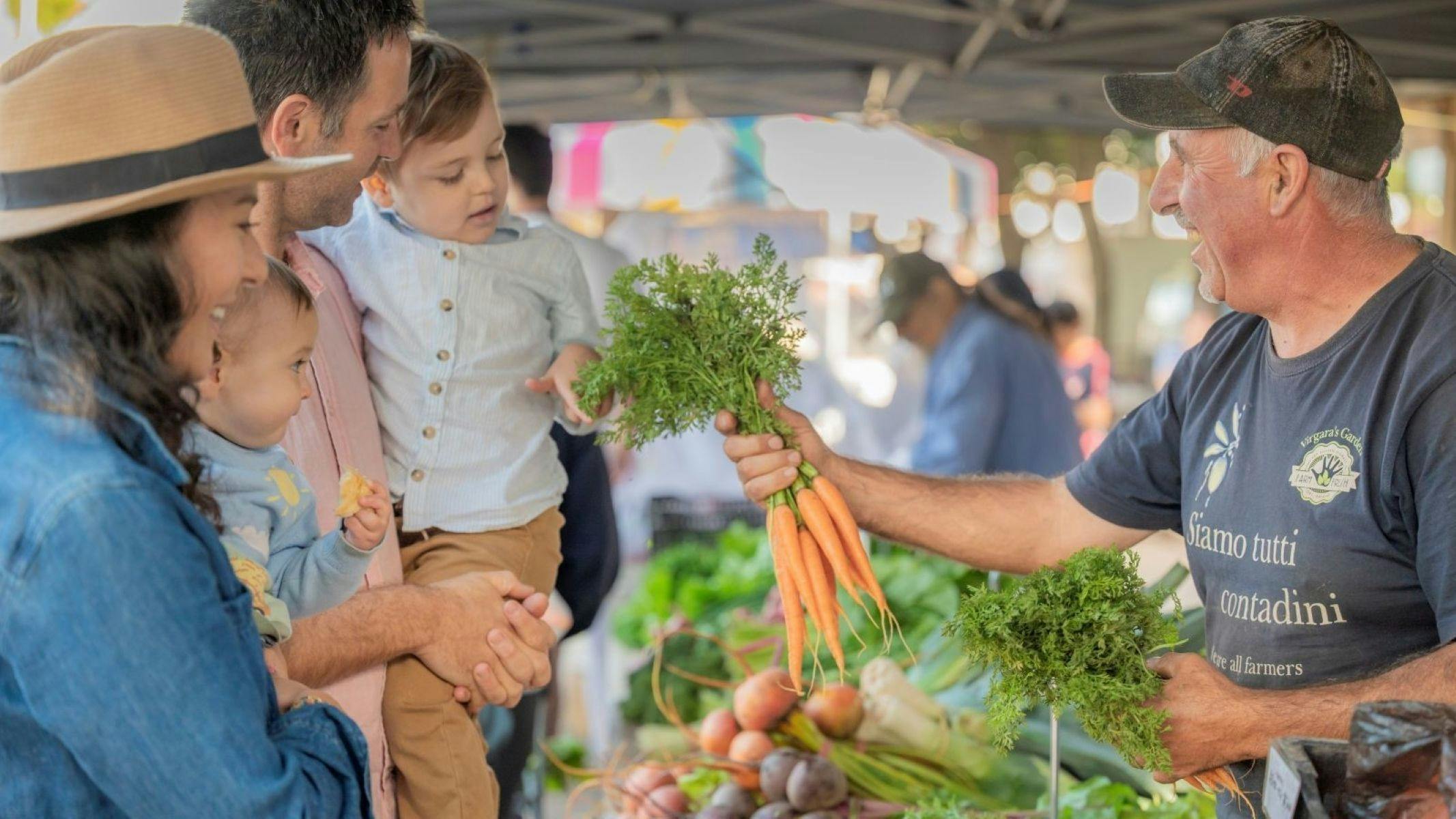 A South Australian farmer chats with a young family while showing them freshly picked carrots at the