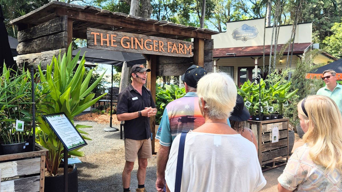 Tour guide standing infront of Ginger Farm sign talking to tour group