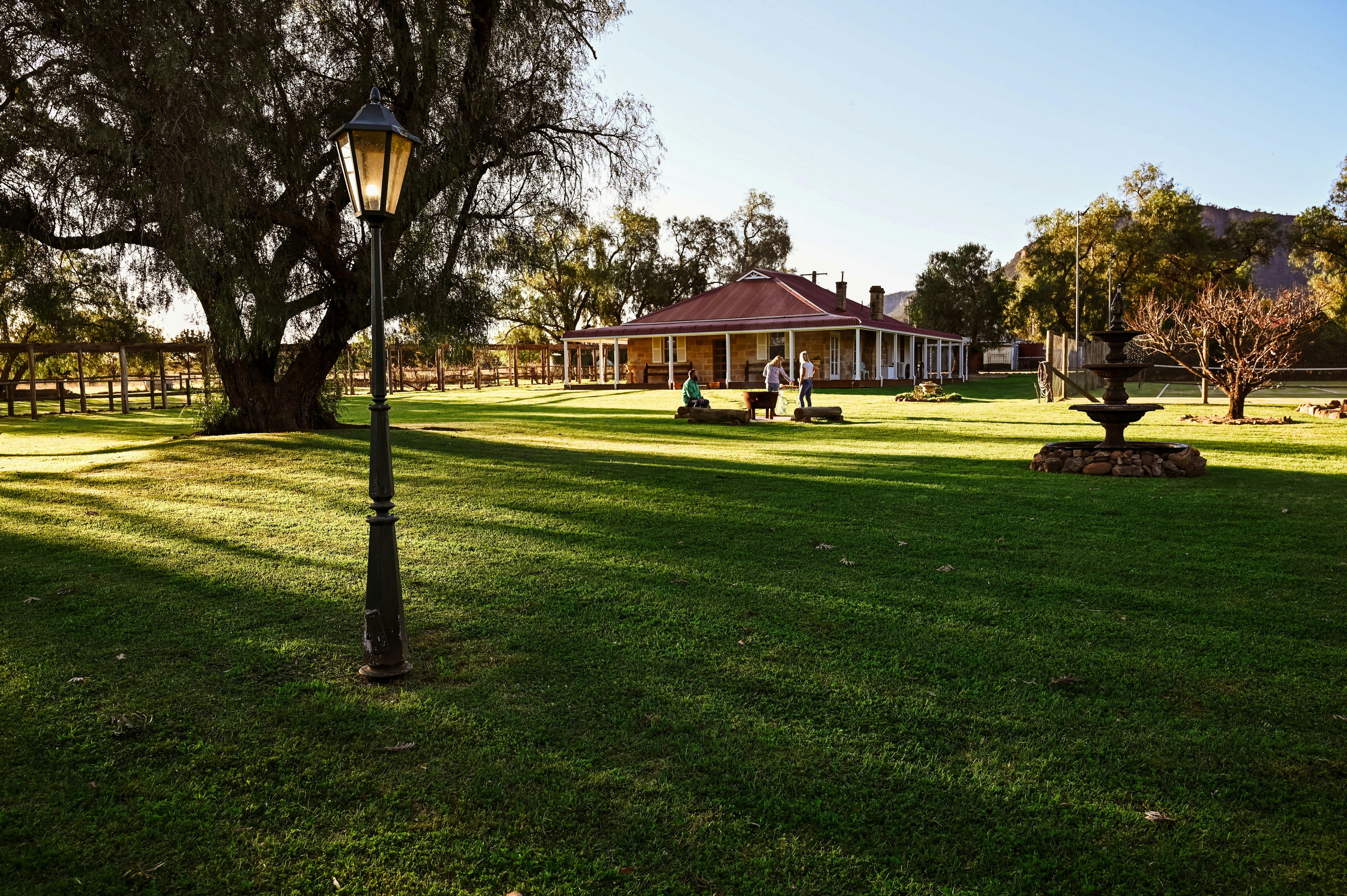 Myalla's backyard looking looking back at the homestead, lush green grass, fountain and garden lamp